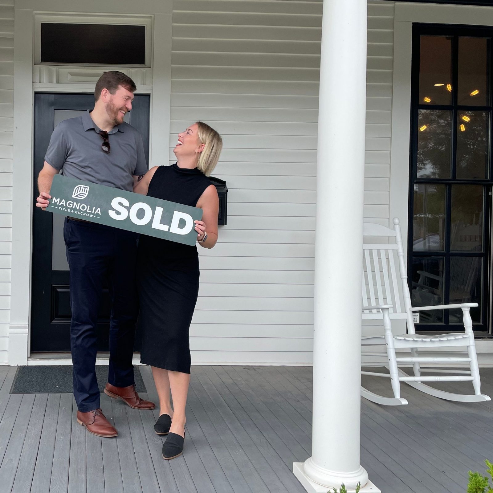 Kayla Brown and a client holding a SOLD sign on a front porch